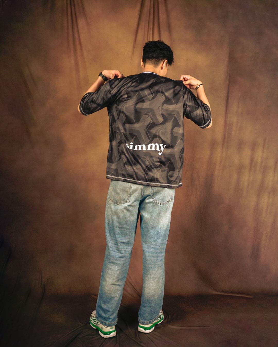 SIMMY Brave New World oversized black jersey with all-over graphic pattern and white logo on back, worn by a man.
