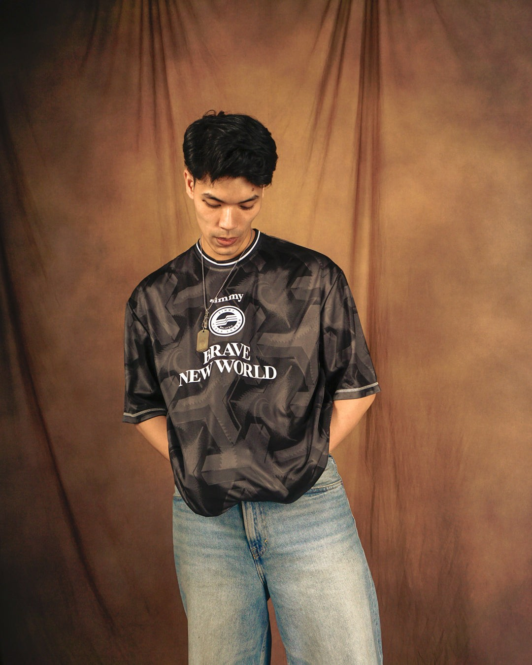 A model wearing a SIMMY black oversized jersey with a bold graphic pattern, woven patch, and flock detailing.