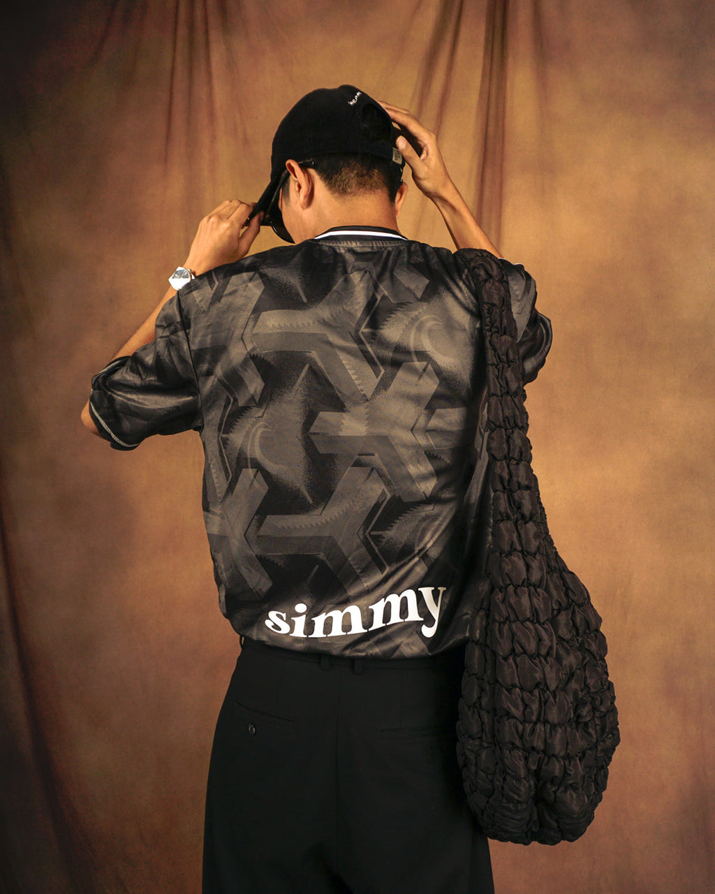 SIMMY Brave New World oversized black jersey with bold graphic pattern and white logo on back, worn by a man.