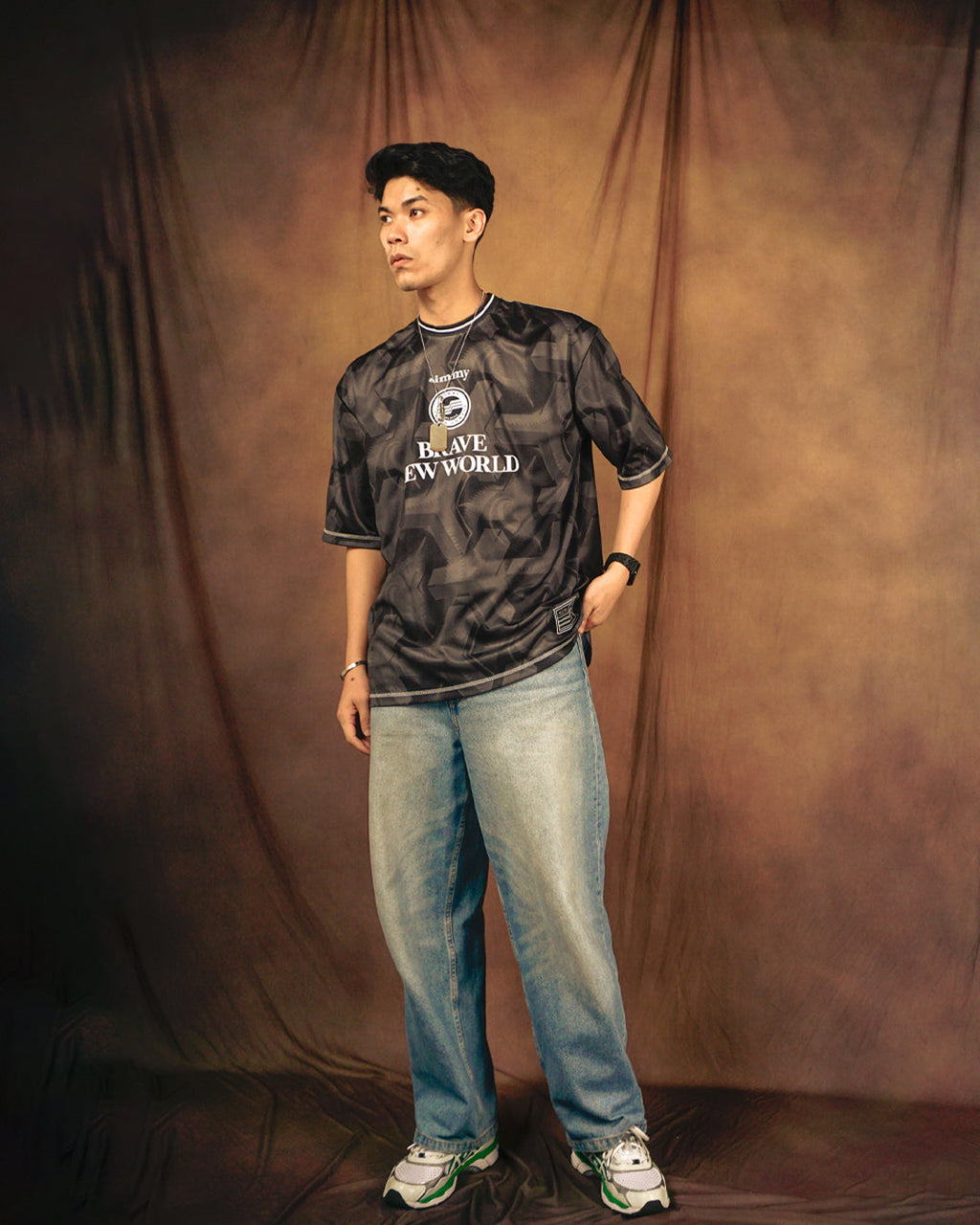 A model wearing a black SIMMY Brave New World oversized jersey with graphic patterns, paired with light blue jeans.